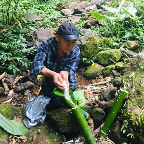 Cooking food in bamboo tubes on the trekking trail led by our local tour guide Cuisson des aliments dans des tubes de bambou sur le sentier de randonnée